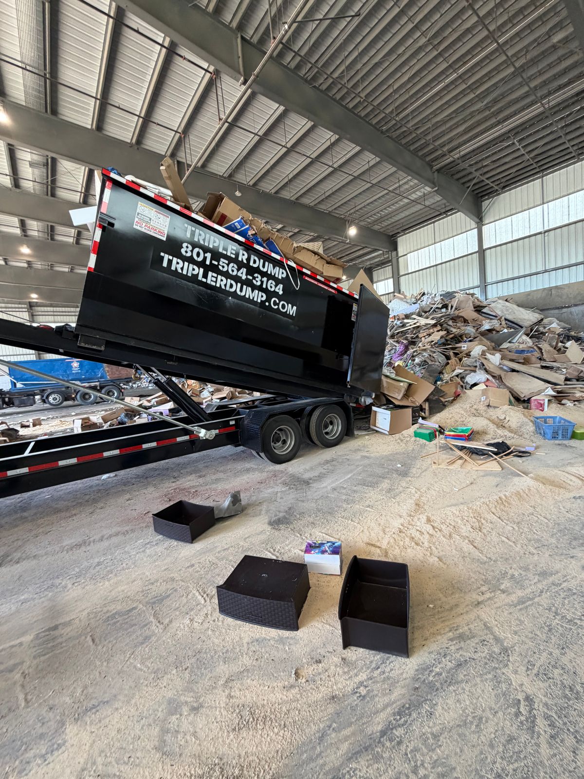 Triple R Dump bin tipping its load inside a covered transfer station