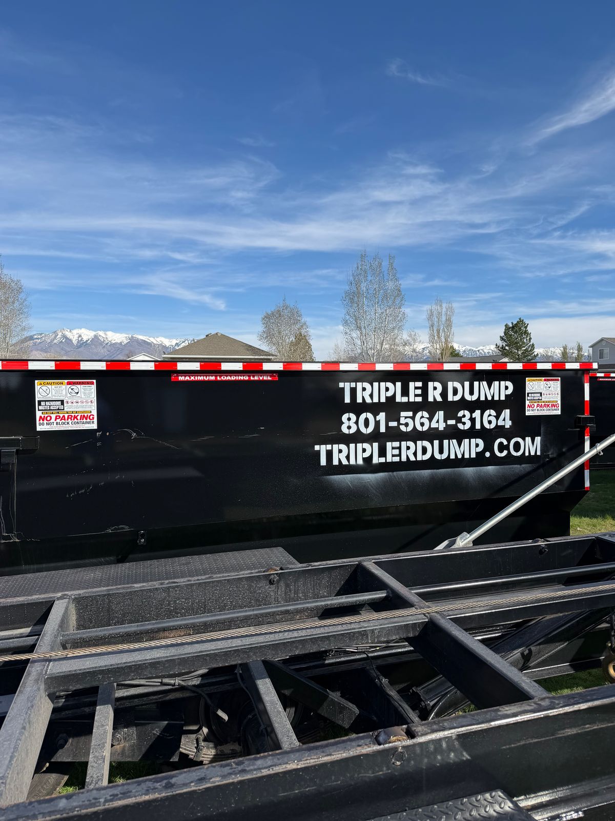 Triple R Dump bin with the phone number painted on its side, on the roll-off trailer